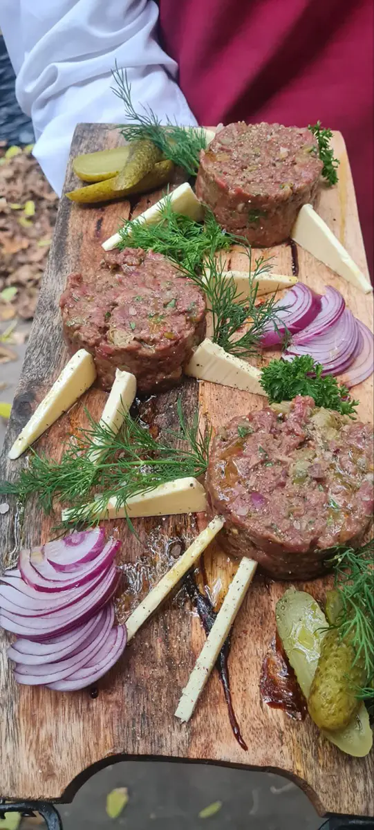 Cevapi served with onions and herbs on a wooden platter