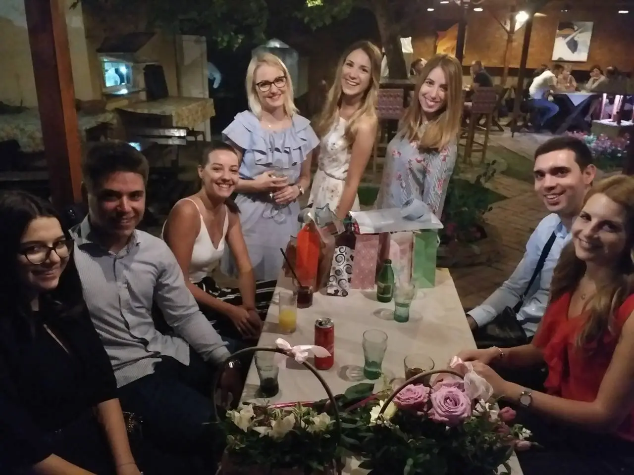 A group of friends smiling for a photo during a private celebration in the garden of Recept restaurant in Belgrade.